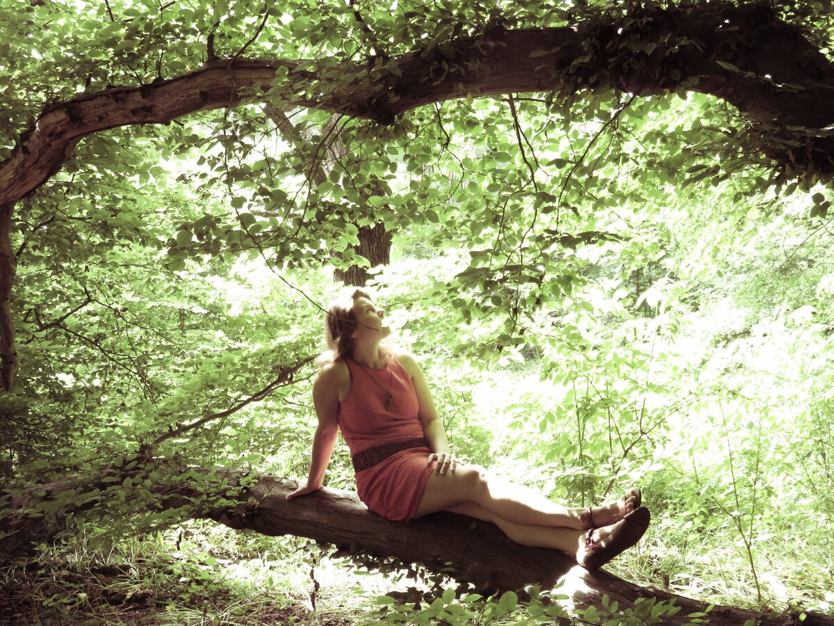 Ein Mensch sitzt still auf einem großen Ast im Wald
